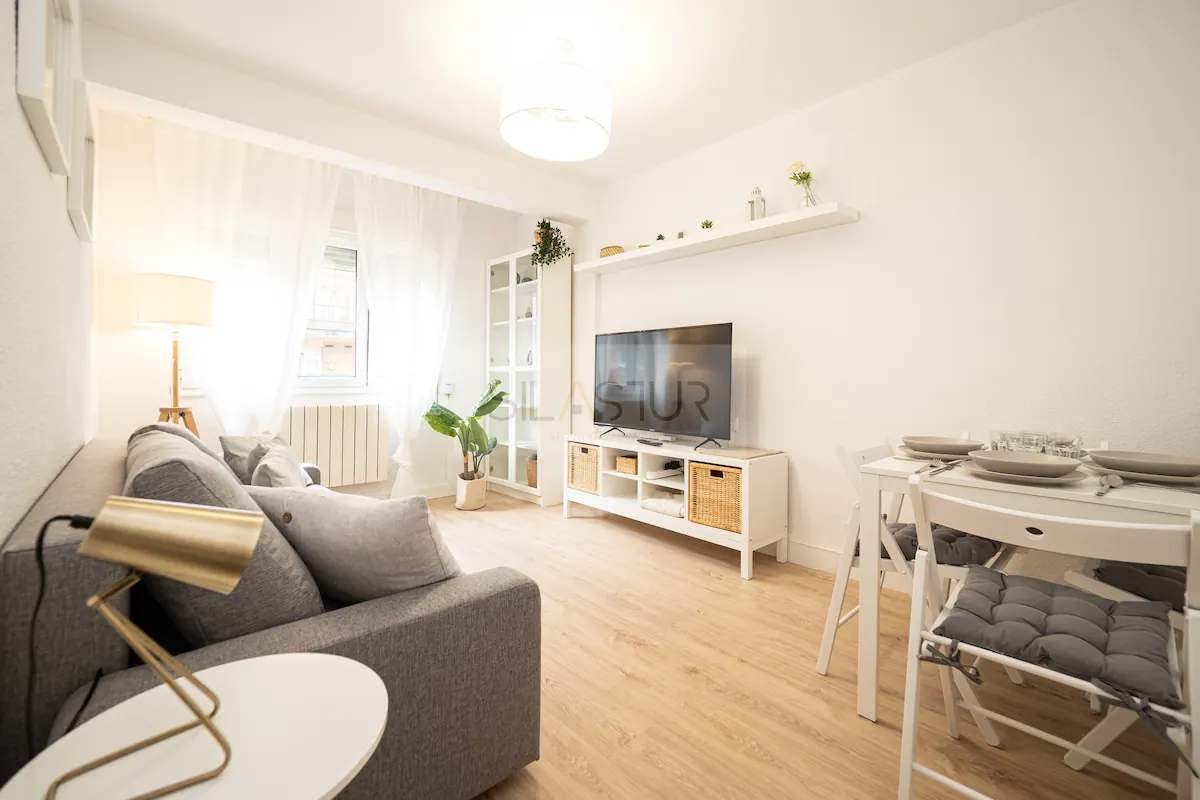 Living room with grey sofa, TV and dining table
